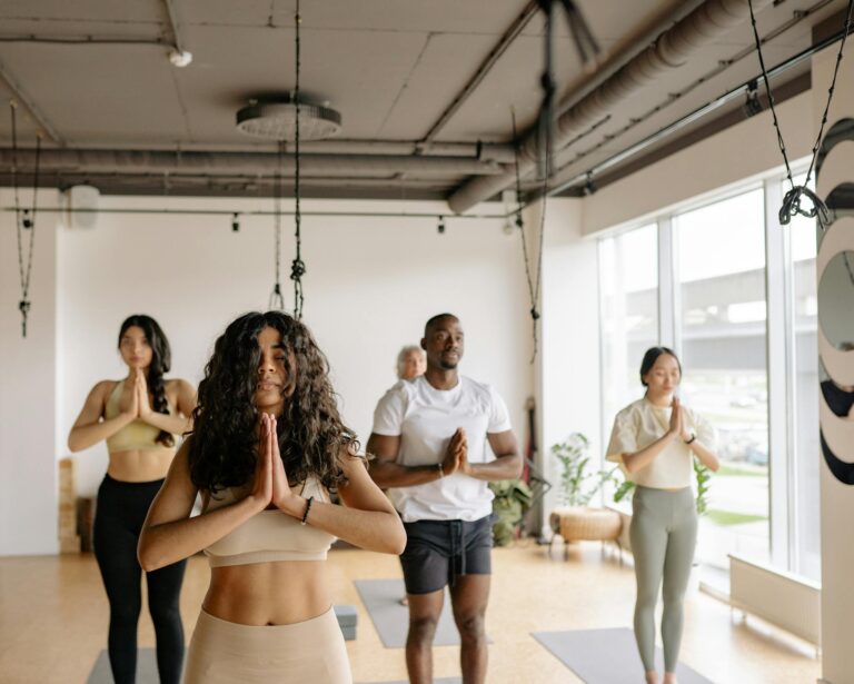 A multicultural group of adults practicing yoga poses together in a bright studio.