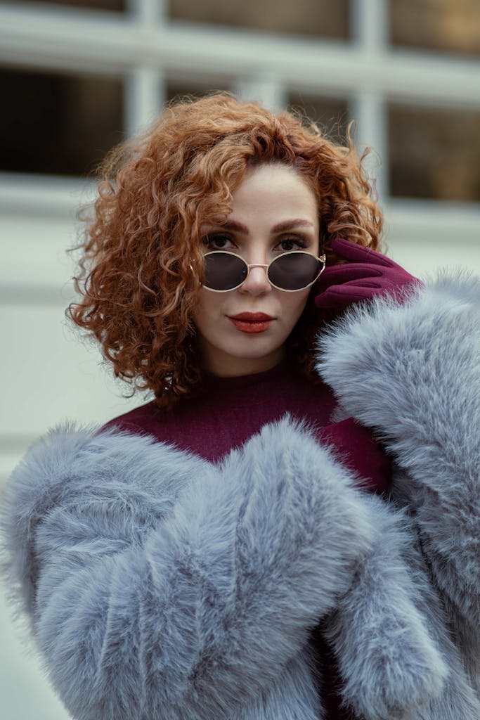 Stylish woman in sunglasses and faux fur coat, balancing winter elegance and modern fashion.